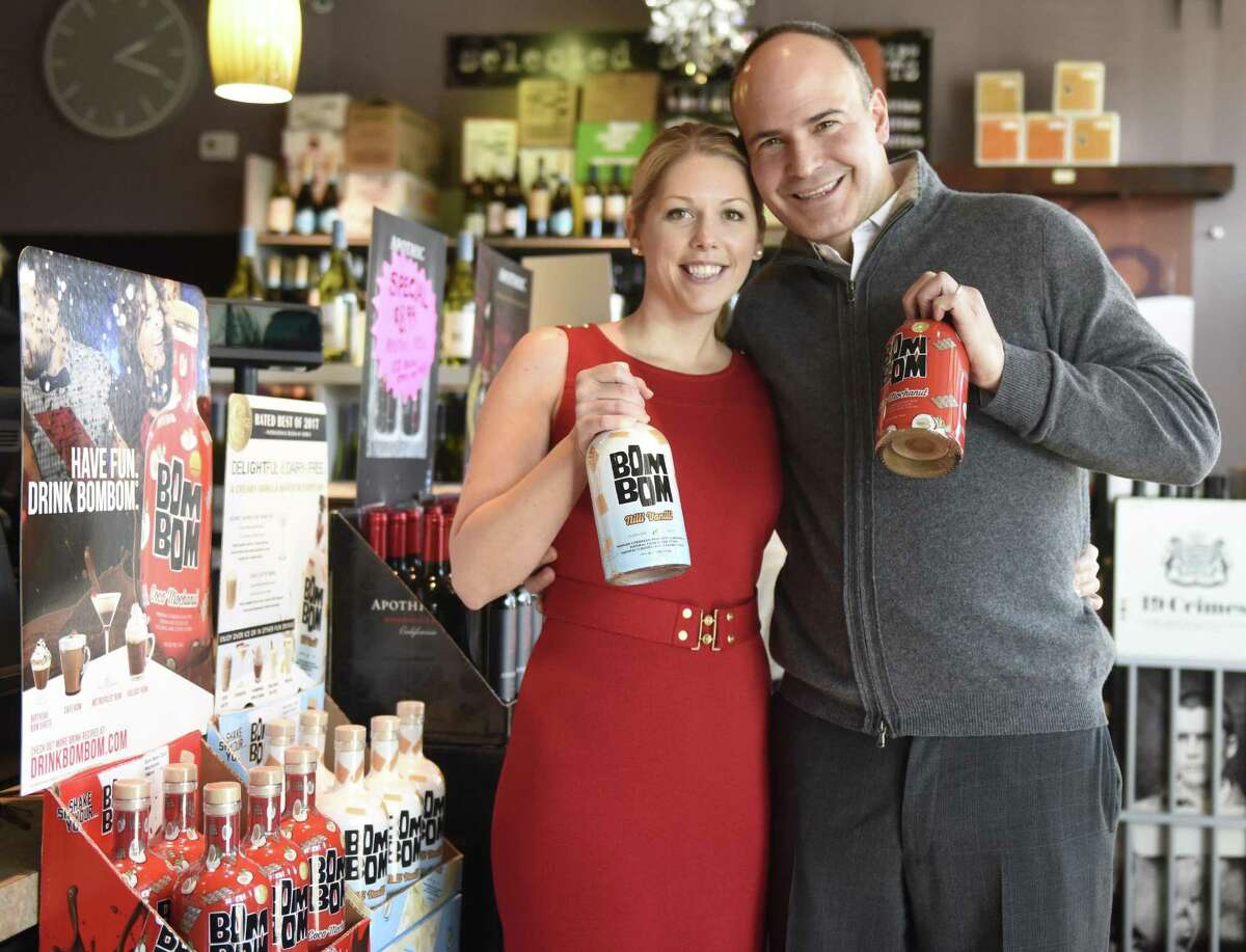 Bom Bom owners, local couple Eva Maria Janerus and Kevin Mowers, pose with bottles of Bom Bom Nilli Vanilli and Coco Mochanut at A1 Cellars Wine and Spirits in the Riverside section of Greenwich, Conn. Monday, Feb. 12, 2018. Coco Mochanut is a blend of Caribbean rum with chocolate, coffee and coconut, while Nilli Vanilli is a blend of Caribbean rum with almond milk and vanilla cookie flavors.
