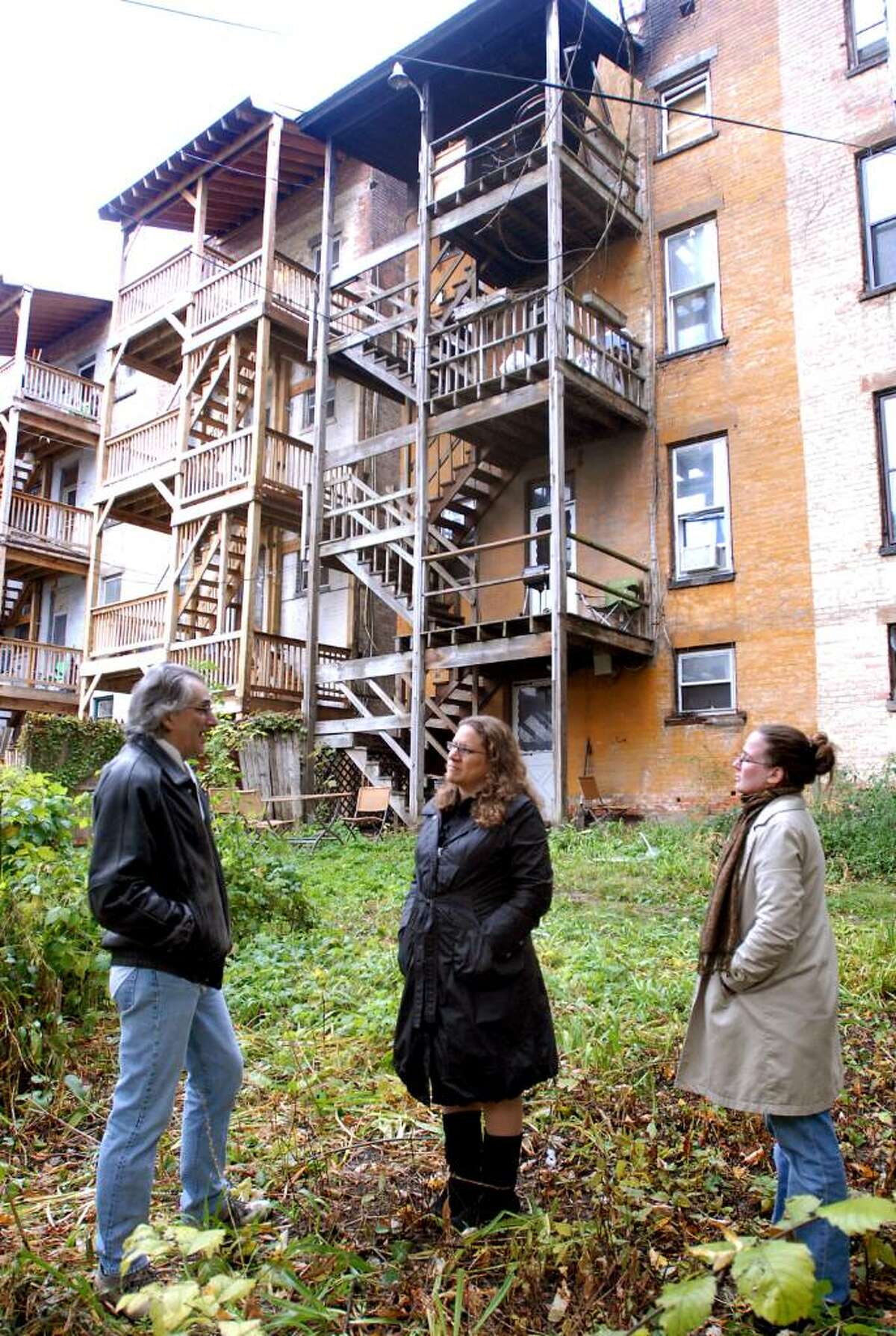Building owner Joseph Galu, left, talks with Susan Holland, center, and Cara Macri, right, both of the Historic Albany Foundation, as they evaluate the backside of 582 Madison Ave. after it was damaged by a fire Monday night in Albany. (Cindy Schultz / Times Union)