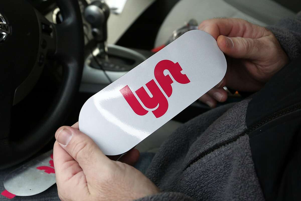 A Lyft driver holds a Lyft logo before installing it on his car on Wednesday, Jan. 31, 2018 in Pittsburgh. (AP Photo/Gene J. Puskar)