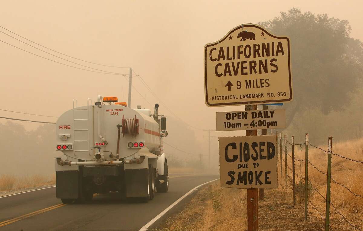 A water truck passes a warning sign that the California Caverns historic site is closed due to smoke from the Butte Fire, Saturday, Sept. 12, 2015, near San Andreas, Calif. Firefighters gained some ground Saturday against the explosive wildfire that incinerated buildings and chased hundreds of people from mountain communities in drought-stricken Northern California. (AP Photo/Rich Pedroncelli)