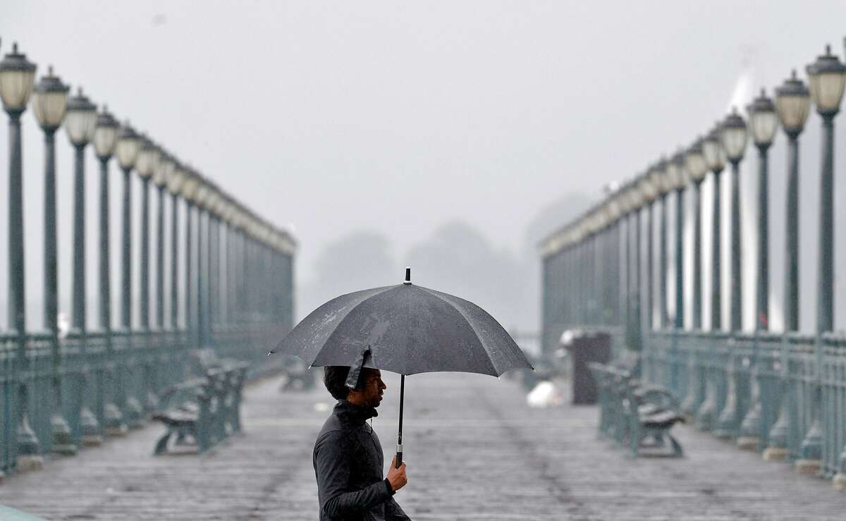 A man carrying an umbrella for protection from the rain walks along the Embarcadero in San Francisco, Calif., Sunday, November 26, 2017, as a storm dropped several inches of rain throughout the bay