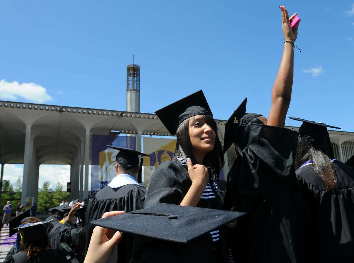 Graduates wave to their families near the end of the UAlbany undergraduate commencement ceremony Sunday in Albany. ( Philip Kamrass / Times Union)