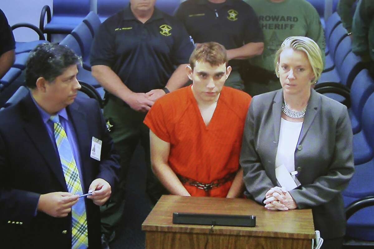 A video monitor shows school shooting suspect Nikolas Cruz, center, making an appearance before Judge Kim Theresa Mollica in Broward County Court, Thursday, Feb. 15, 2018, in Fort Lauderdale, Fla. Cruz is accused of opening fire Wednesday at Marjory Stoneman Douglas High School in Parkland, Fla., killing more than a dozen people and injuring several.
