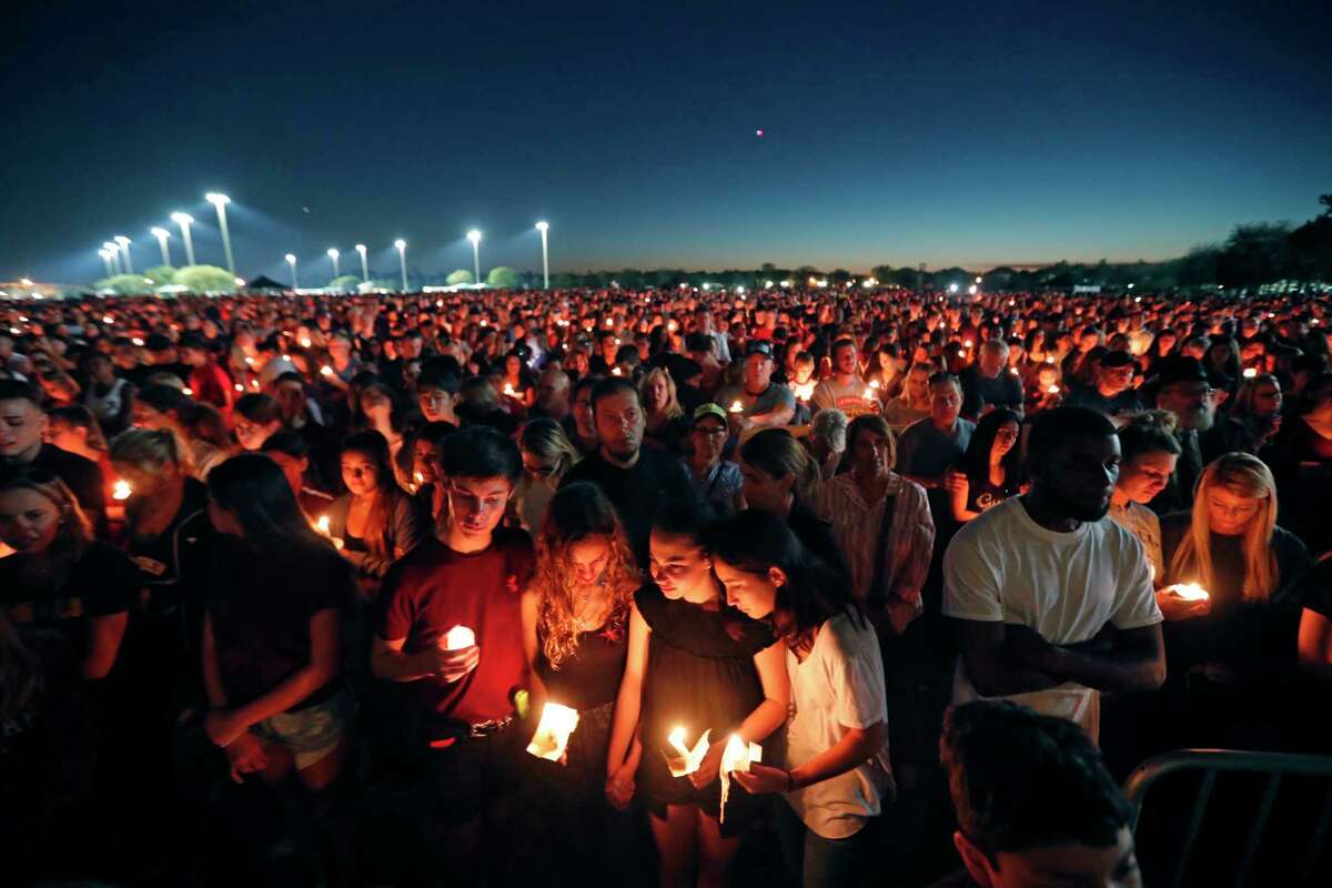 People attend a candlelight vigil Thursday for the victims of the Wednesday shooting at Marjory Stoneman Douglas High School, in Parkland, Fla.﻿. ﻿Among the dead were teachers and students: a popular football coach, a soccer player and a trombonist in the ﻿band.