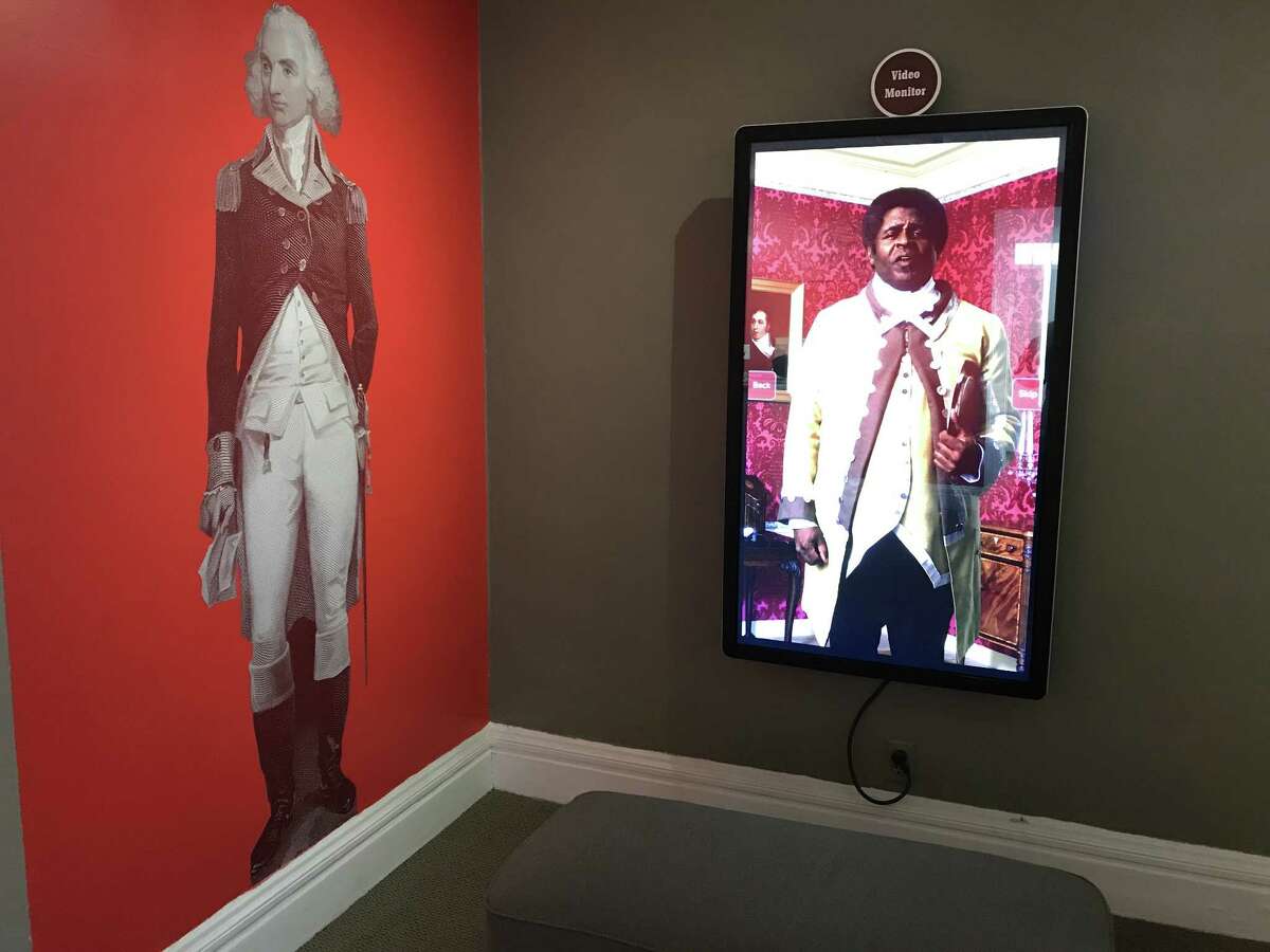 Part of the exhibit at the Schuyler Mansion visitor center, where Philip Schuyler, at left, shares a room with enslaved butler Prince, portrayed by an actor in a video at right. (photo by Amy Biancolli)