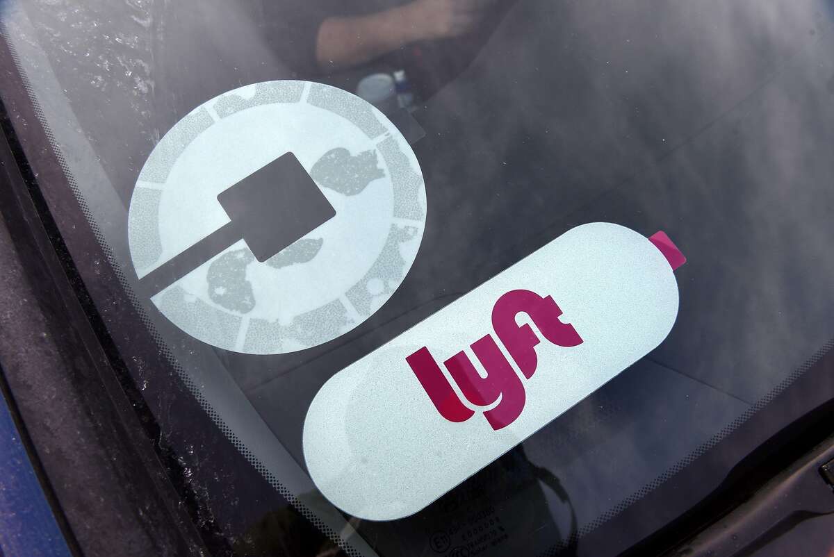Uber and Lyft stickers are shown in a driver's windshield at the ride-hailing parking lot near Albany International Airport on Friday, Dec. 29, 2017, in Colonie, N.Y. Uber and Lyft will be available on New Year's for the first time in the Capital Region. (Will Waldron/Times Union)