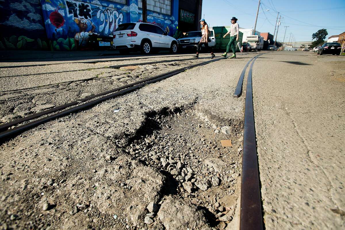 Pedestrians pass a pothole on 18th St. in Oakland, Calif., on Saturday, Feb. 3, 2018. Roads throughout the Bay Area are slowly improving, according to a new report, and officials at the Metropolitan Transportation Commission are crediting an infusion of SB1 gas tax dollars for the gradual upward trend.