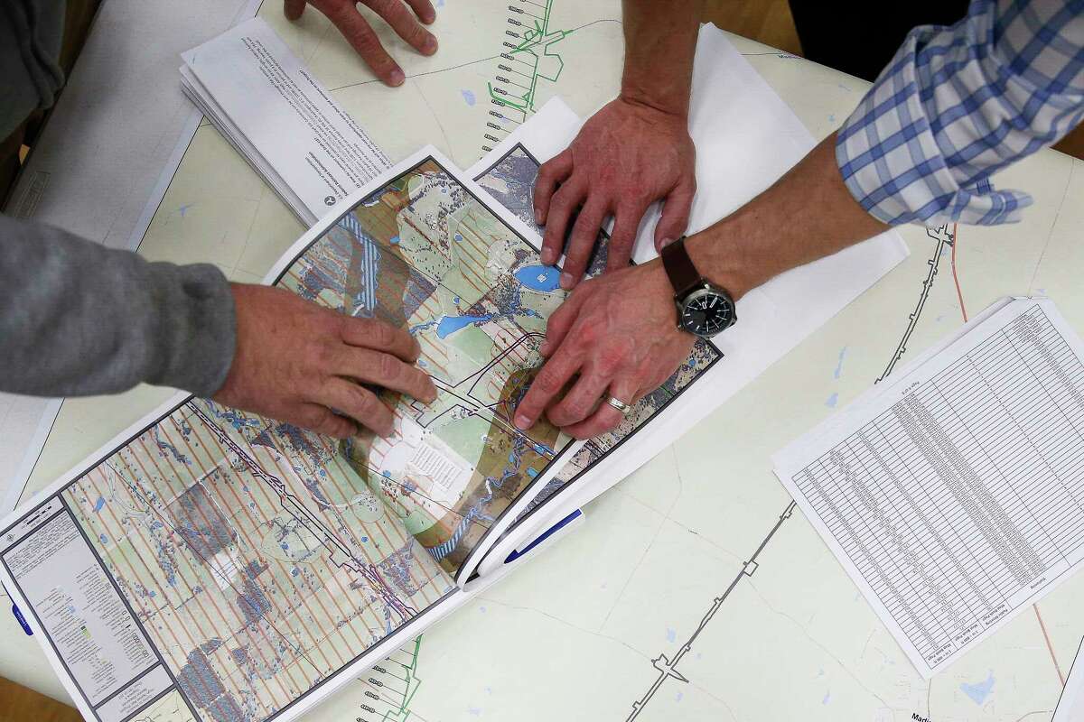Matt Schiel, left, looks at a map of the Houston-to-Dallas bullet train going through the middle of his property with AECOM environmental planner Reggie Herman during a public hearing held by the Federal Railroad Administration to discuss the high-speed train on Feb. 5 in Cypress.