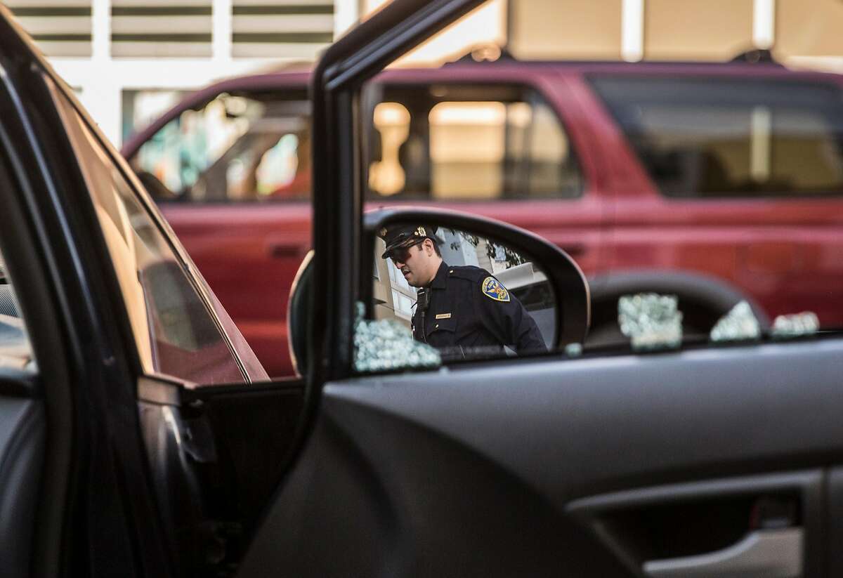 Mission District San Francisco Police Officer Robert Clendenen is seen in the reflection of Michael Lech's rear view mirror as he investigates a car break-in near Potrero Street and 24th Avenue Thursday, Feb. 1, 2018 in San Francisco, Calif.