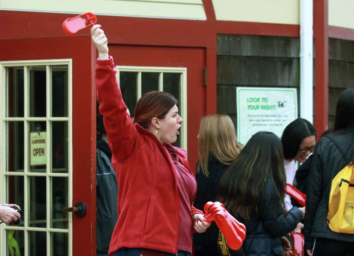 Volunteer Chandra Gioiello hands out noisemakers to ward of evil spirits during Beardsley Zoo's Asian New Year celebration in Bridgeport, Conn., on Saturday Feb. 17, 2018. This year, 4716, is the year of the dog. Sone of the activities included a visit with the zoo's real dogs like Mexican wolves, red wolves, maned wolves and even a grey fox. There were also activities like fortunes, Chinese checkers, story-time and coloring.