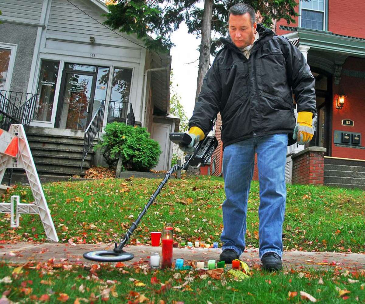 JOHN CARL D'ANNIBALE/TIMES UNION-- Albany Police Forensic unit's Victor Pizzola uses a metal detector Wednesday morning October 22, 2008, to search for evidence near the make-shift memorial for UAlbany student Richard Bailey, who was shot - and subsequently killed Monday night near the corner of Yates and South Lake in Albany.