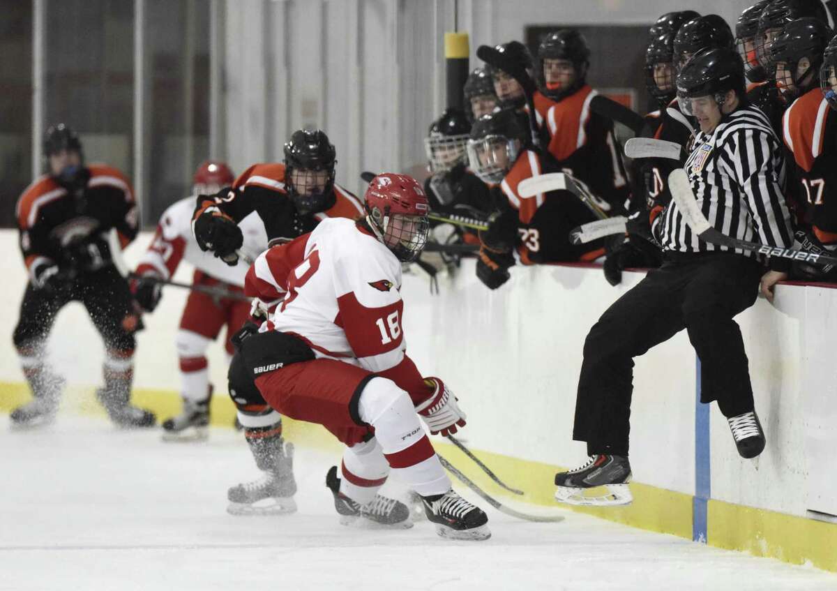 Greenwich's Connor Santry (18) and Ridgefield's Nick Cullinan (2) scramble for the puck as a referee jumps to avoid contact in Greenwich's 5-3 win over Ridgefield in the high school boys hockey game at Dorothy Hamill Skating Rink in Greenwich, Conn. Monday, Feb. 19, 2018.
