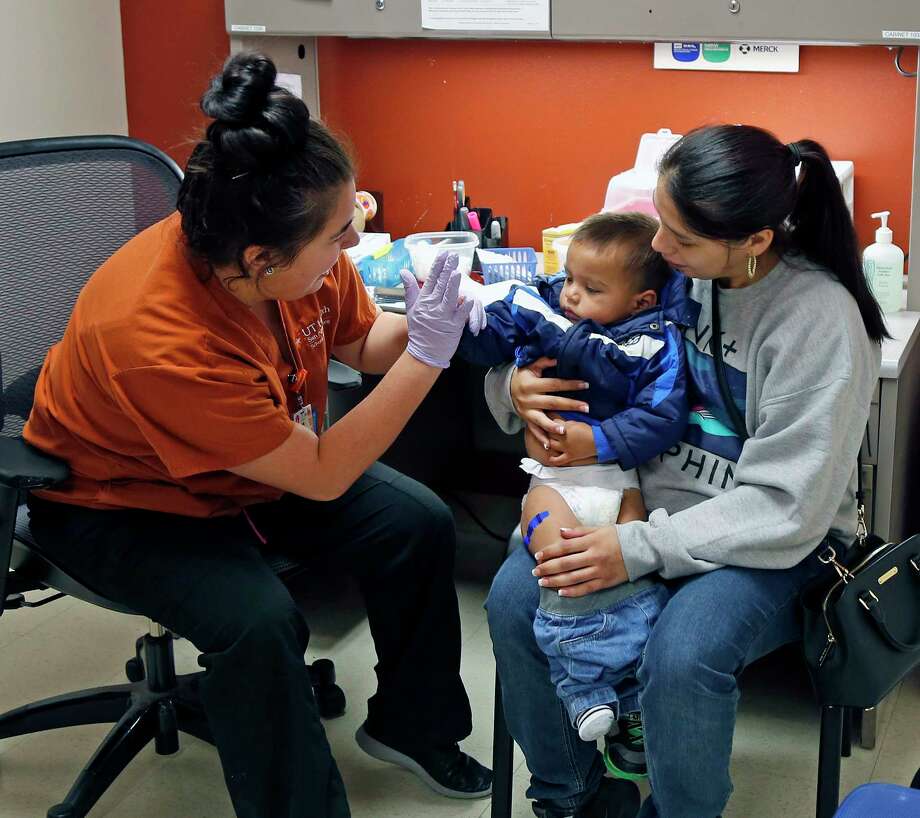 Caitlin Garcia, a student at the UT-San Antonio School of Nursing, gives a high-five to Alexander Almanza, 2, after administering his flu shot while he was held by his mom, April. It's not too late to get inoculated this season, officials say. Photo: Ronald Cortes, For The San Antonio Express News / 2017 Ronald Cortes