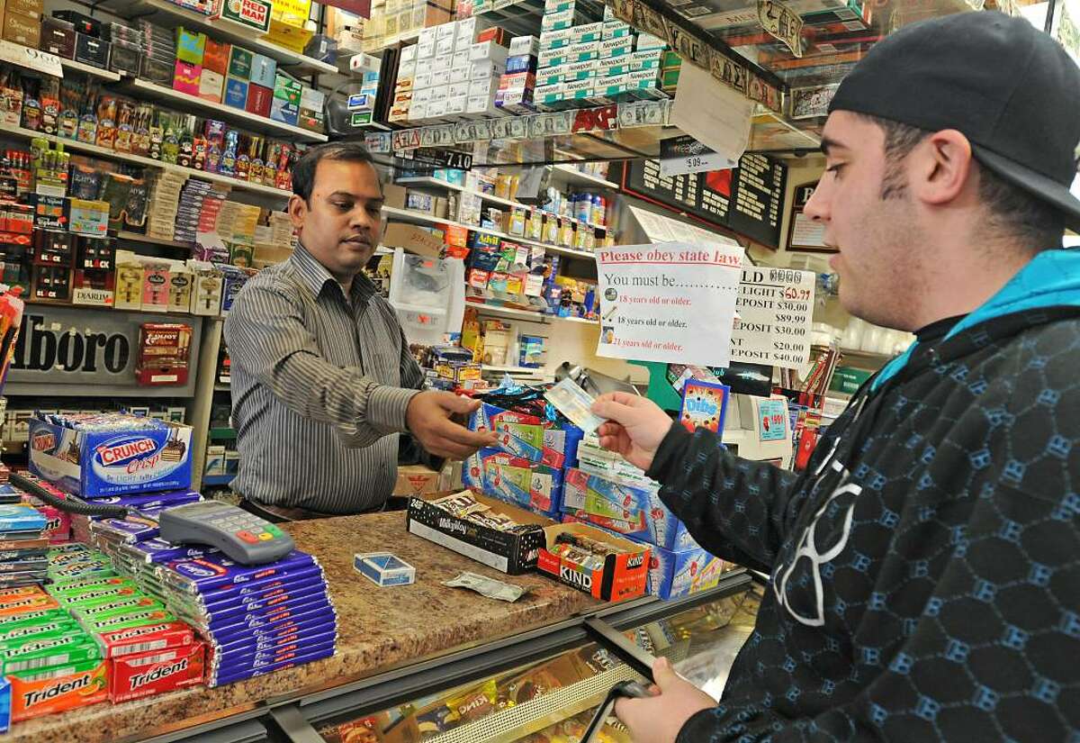 Ashif Mashud checks the ID of Marco Scalia at Easha Convenience store. (Lori Van Buren / Times Union)