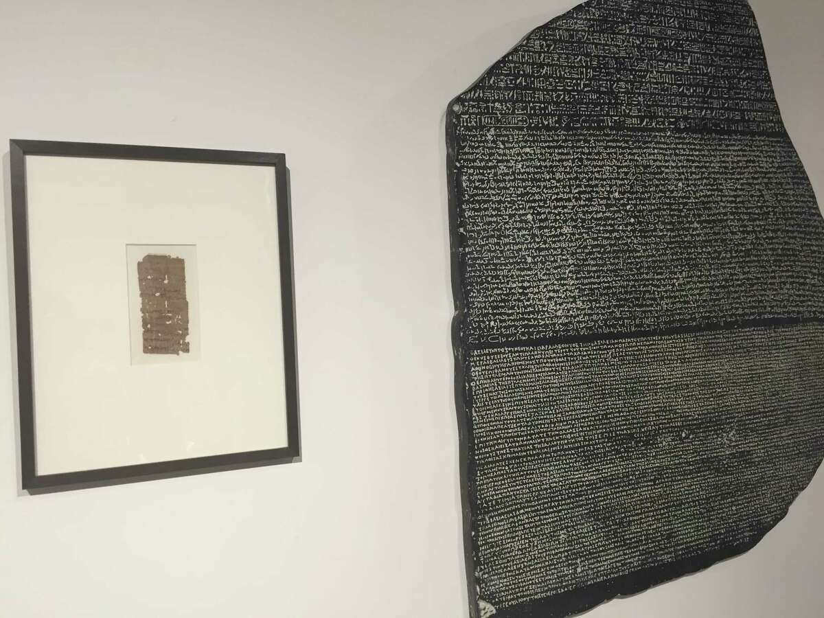 A papyrus fragment with Greek writing from 300-350 B.C.E and a replica of the Rosetta Stone.