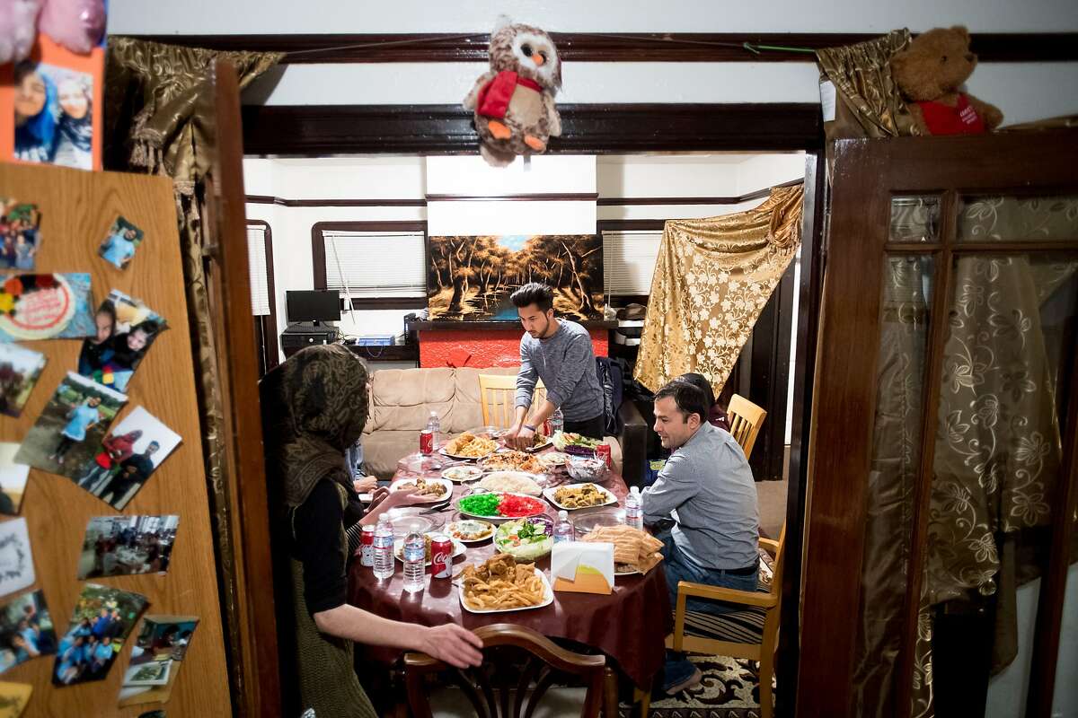 Shaheen Nassimi, 20, standing, serves food as his family eats dinner in their Oakland, Calif., home on Sunday, Feb. 11, 2018. Seated at right is his father Abdul Nassimi.