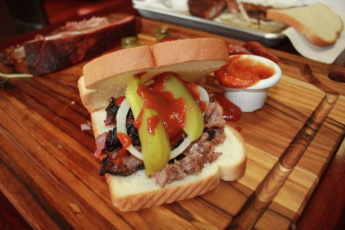 A brisket sandwich assembled at the table and slathered in barbecue sauce from El Monte BBQ.