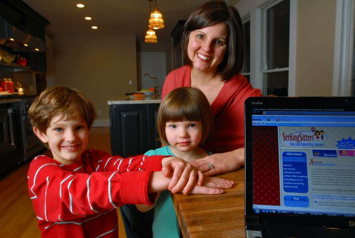 Lori Flynn is the Albany / Saratoga franchise owner of Seeking Sitters, an online babysitting service, is shown with her children Lucia, 3, right, and Hudson, 8, left, in the kitchen of their Delmar, NY home. (Philip Kamrass / Times Union)