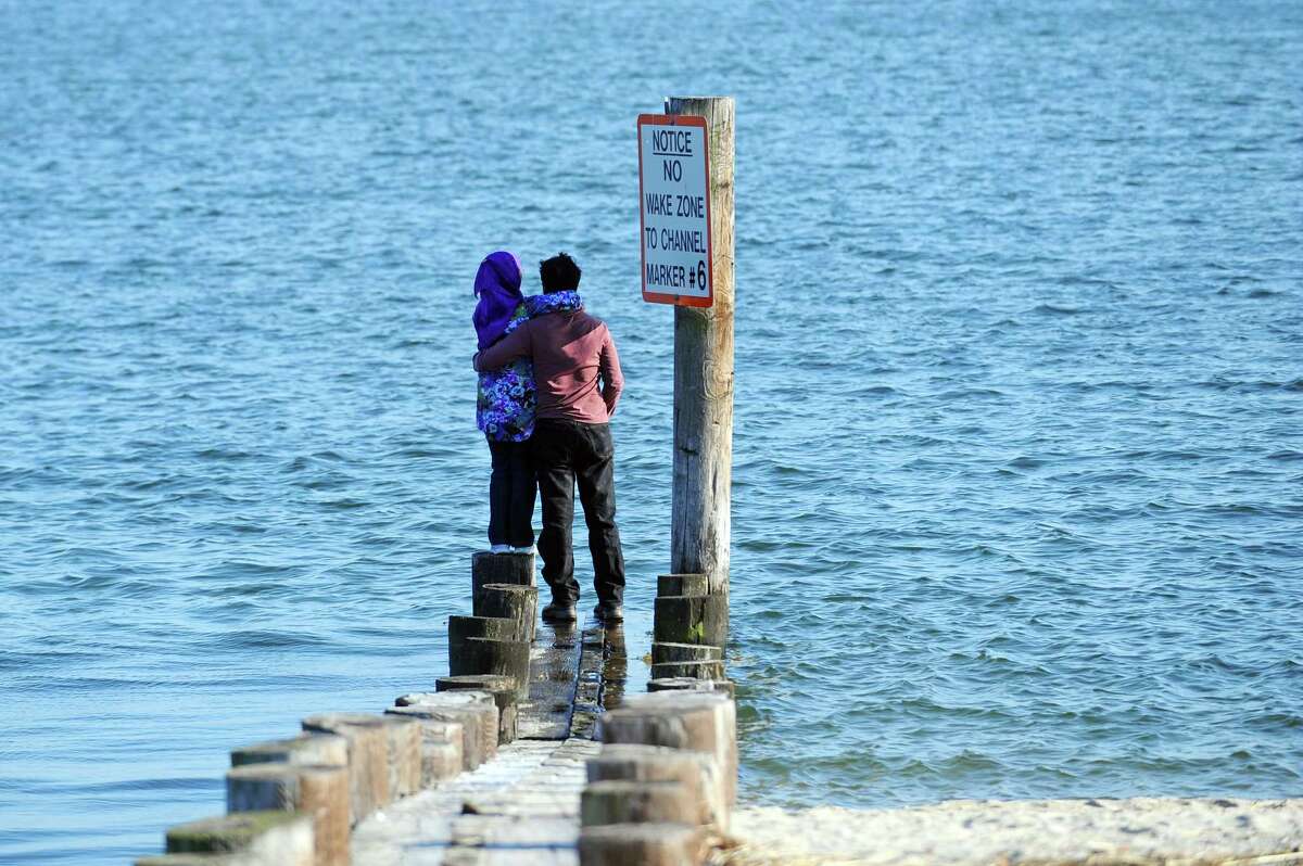 A young couple stands in embrace while looking out onto the Long Island Sound at West Beach in Stamford, Conn. on Wednesday, Feb. 21, 2018.