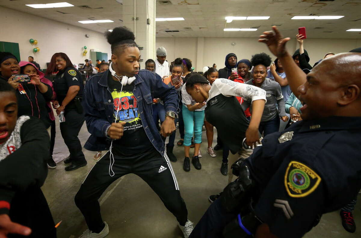 Worthing High School student Darius Scott, center, battles Houston Police officer Randall Winn, right, on the dance floor during the first Police Officer Appreciation Luncheon Wednesday, Feb. 21, 2018, in Houston. The school has partnered with the police department in an effort to increase positive interaction between students and officers.