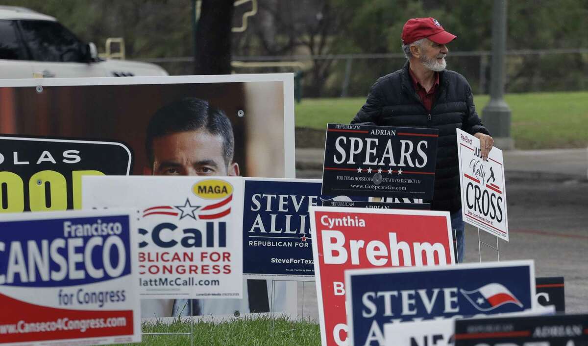 Jim Mathis looks to place a campaign sign near a San Antonio polling site on the first day of early voting. Early voting in Texas runs though March 2.