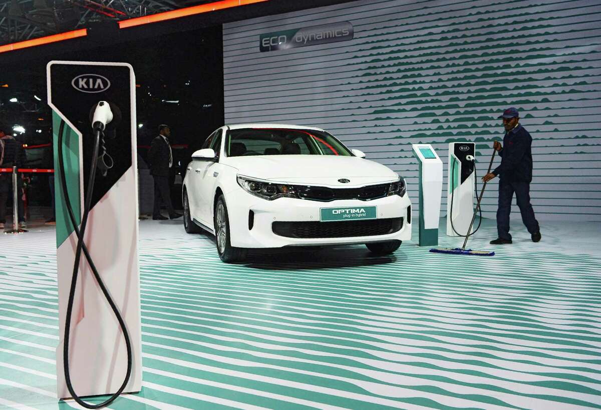 This photograph taken on February 7, 2018 shows a worker cleaning the floor near KIA's electric hybrid OPTIMA car during the Indian Auto Expo 2018 in Greater Noida. Electric cars have basked in the limelight at the flagship auto show in India, where an ambitious plan to phase out polluting clunkers has manufacturers racing to lure millions of new drivers to their green vehicles. / AFP PHOTO / SAJJAD HUSSAIN / TO GO WITH India-economy-auto-AutoExpo2018,FOCUS by Abhaya SrivastavaSAJJAD HUSSAIN/AFP/Getty Images