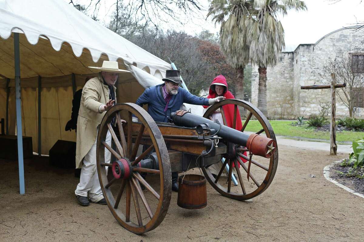 Alamo living historians Tom Hicks, left, and John Potter, center, demonstrates rolling an 1100-pound period canon while Michelle Hill holds open the tent at the Alamo, Wednesday, Feb. 21, 2018. The Alamo will have a full 13 days of lectures, re-enactments, demonstrations and ceremonies commemorating the 13-day siege and battle of 1836, starting Friday, including evening tours on the Alamo grounds, a free screening of the 1960 John Wayne movie and a lecture by premier Alamo artist Gary Zaboly.