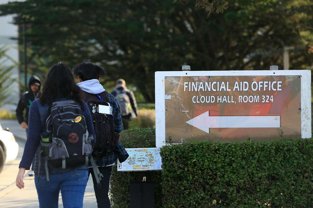 People walk past a directional sign for the financial aid office at City College of San Francisco on Friday, December 8, 2017 in San Francisco, Calif.