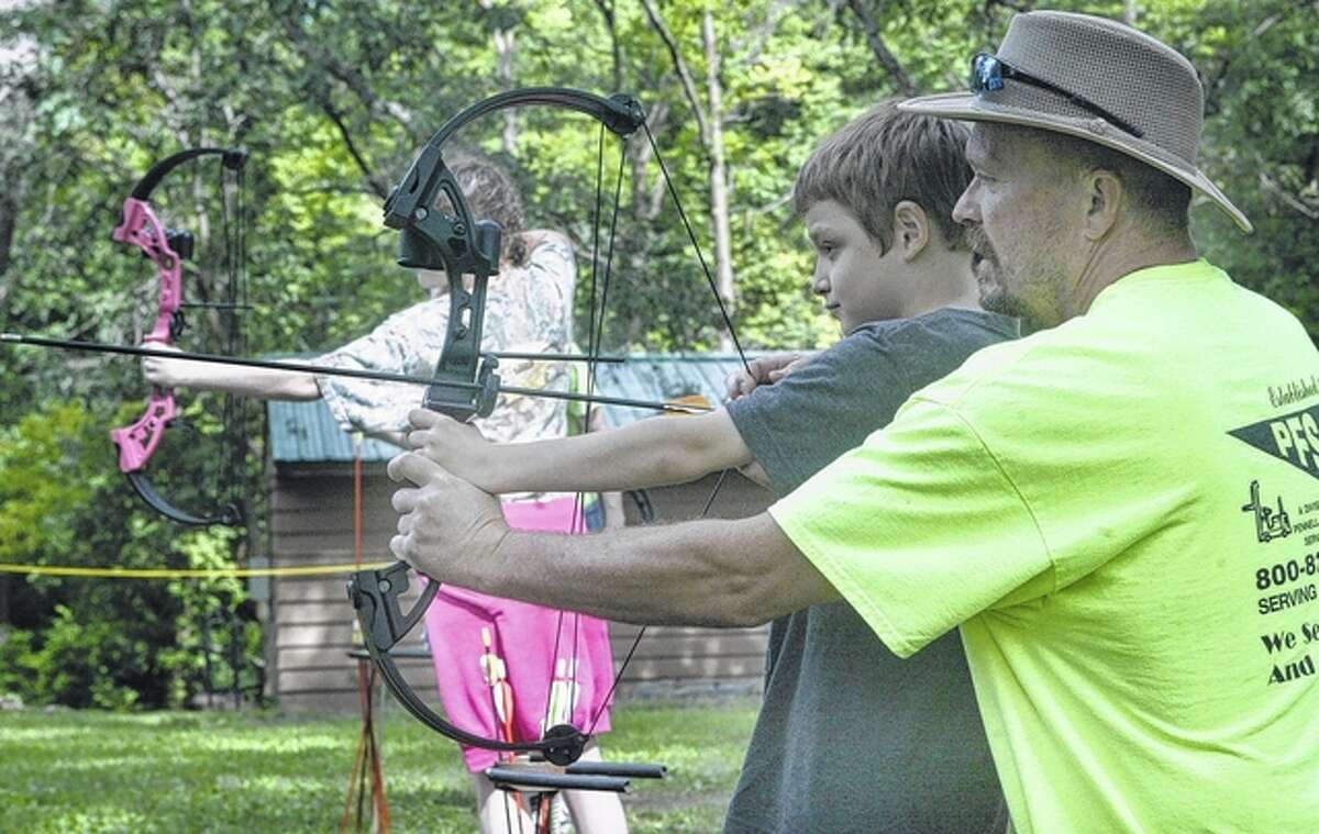 Camp Courage co-director John Hunter helps a young camper on the archery range.