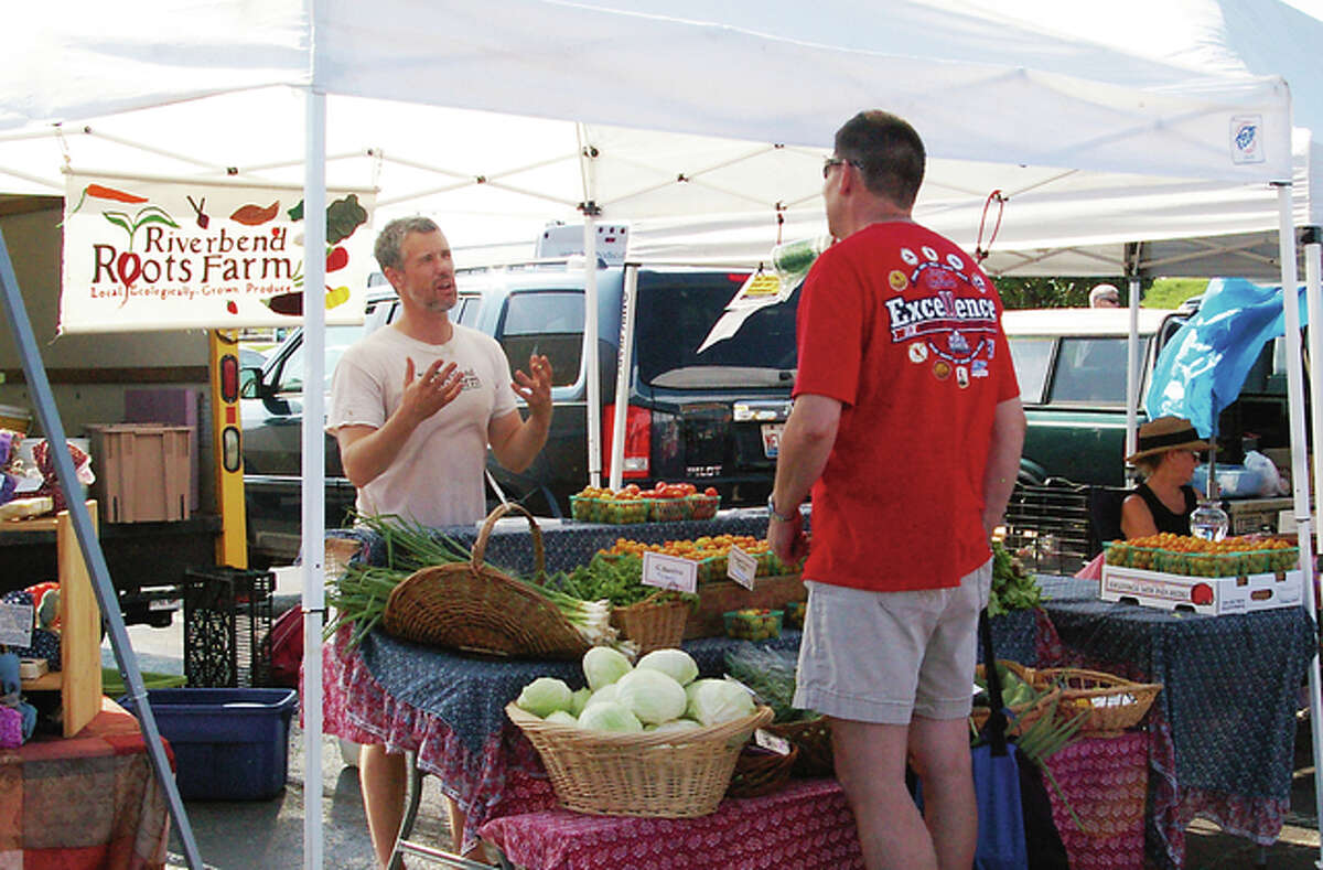 Kris Larson of Riverbend Roots Farm talks to a customer about his organic, sustainably grown produce at the Alton Farmers and Artisans Market Saturday.