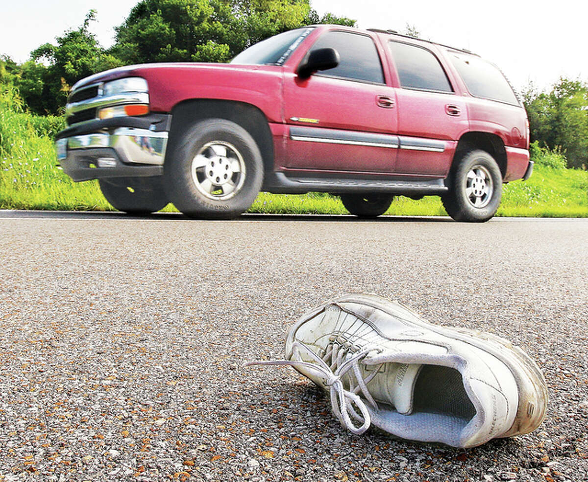 A vehicle passes a shoe from the victim of a fatal car crash involving a vehicle and a pedestrian Monday morning on Illinois Route 140 east of Powder Mill Road. The man’s body was found in the eastbound lanes along with the car that struck him, but this shoe ended up in the westbound lanes of the highway.