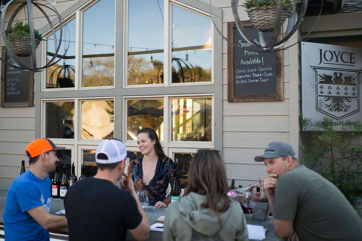 Wine educator Michaela Caul (center) pours for customers at Joyce Vineyards’ newly built outside bar at its tasting room in Carmel Valley.
