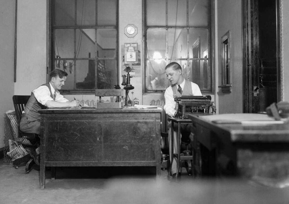 Two newspapermen play their craft in a small newsroom. (Photo by Kirn Vintage Stock/Corbis via Getty Images)
