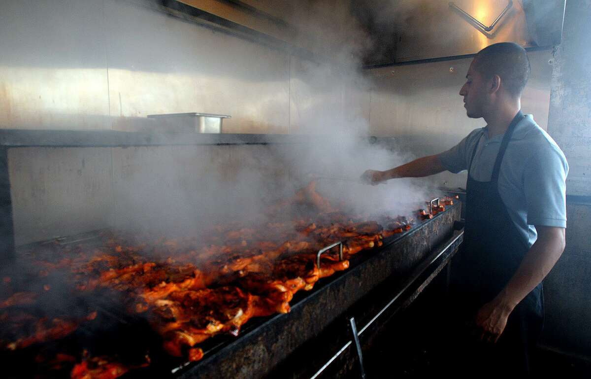 Pollos Asados Los Nortenos employee Azael Rodriguez cooks chickens over a mesquite fired grill in2013.