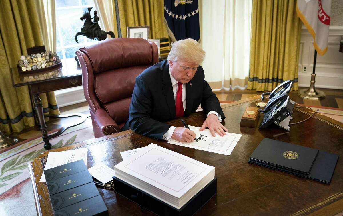 President Donald Trump signs the tax reform bill in the Oval Office of the White House in Washington, Dec. 22. Support for the law is growing even among Democrats, buoying Republican hopes for this years congressional elections.