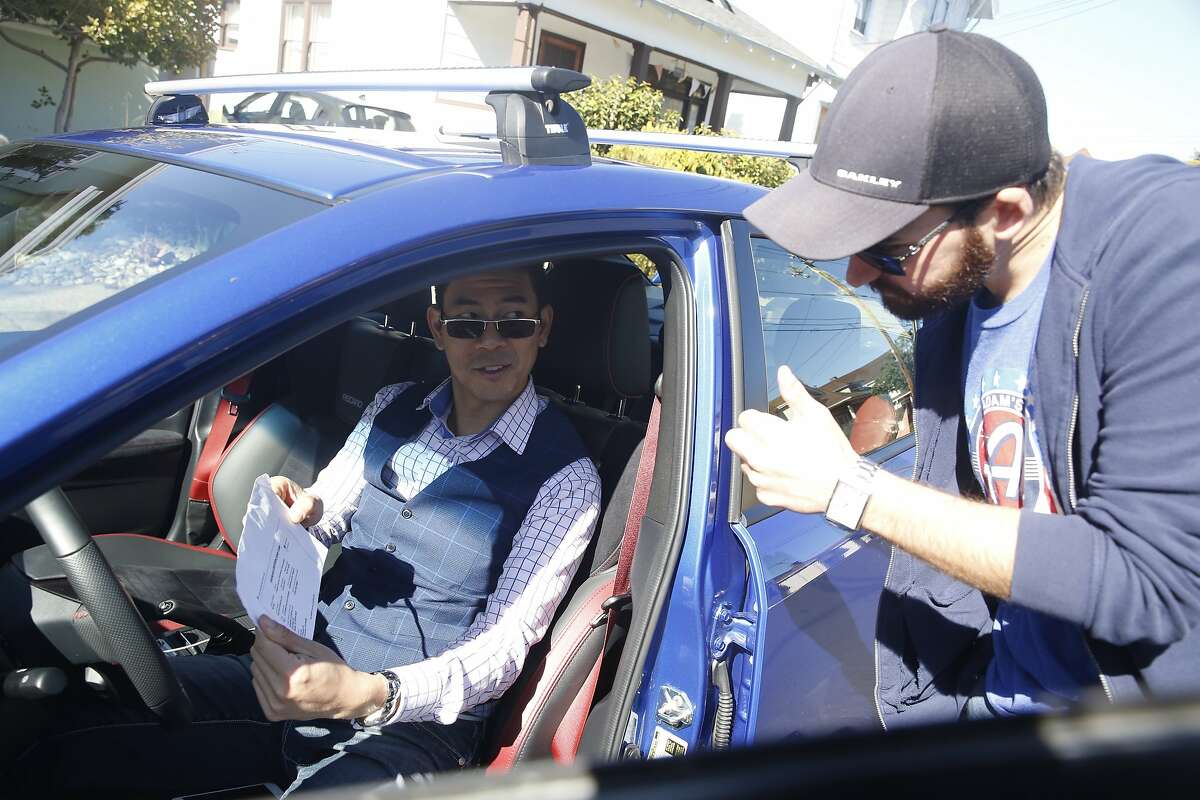 Tyler Karon (right) gives a thumbs up as David Chu (left) shows him the car insurance as Karon picks up Chu's car which he rented through Turo in Alameda, Calif., on Friday, February 23, 2018.
