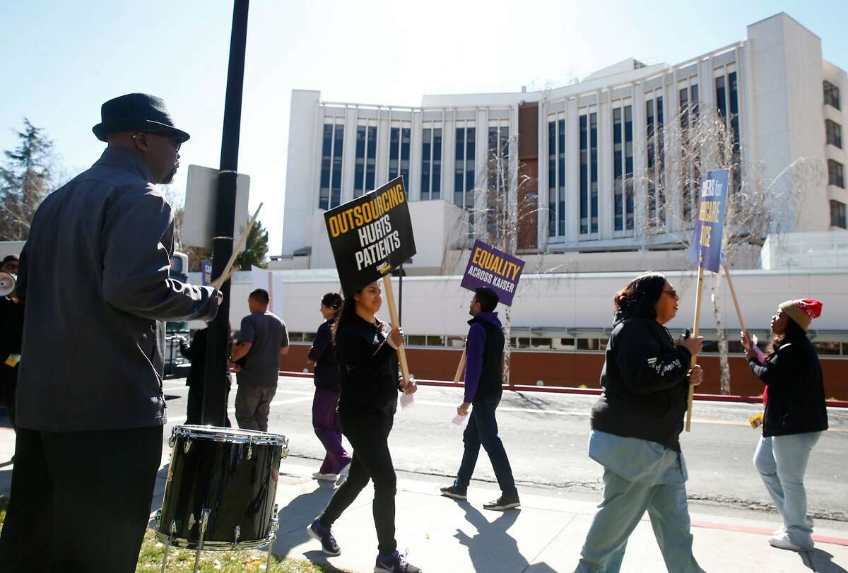 Adefolarin Aforiogun (left) bangs on a drum as healthcare workers, concerned about job cuts and outsourcing, stage a rally outside of the Kaiser Permanente Medical Center in San Jose, Calif. on Friday, Feb. 23, 2018.