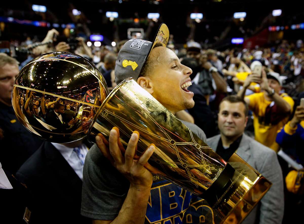 Golden State Warriors' Stephen Curry carries the Larry O'Brien Trophy off the court after defeating Cleveland Cavaliers in Game 6 of NBA Finals at Quicken Loans Arena in Cleveland, Ohio, on Tuesday, June 16, 2015.