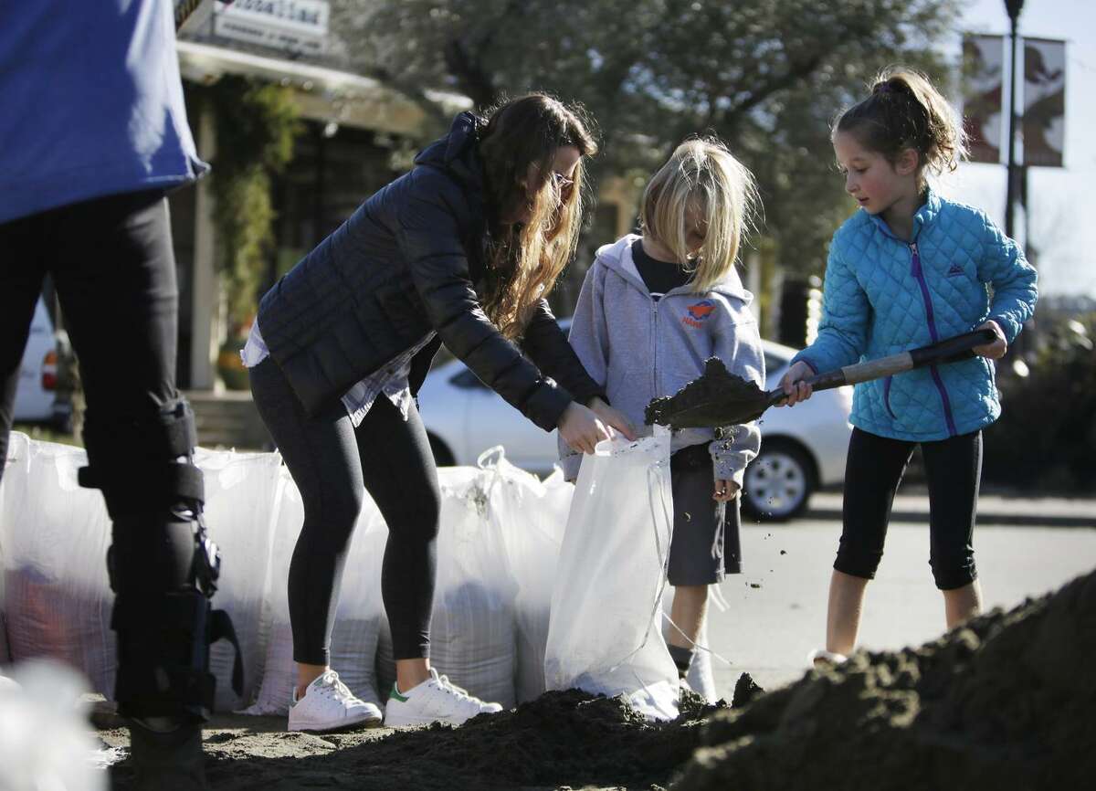 Jenny (left), Isaac and Liat Holden fill sandbags for their home along Sunny Hills Drive in San Anselmo in January 2017.