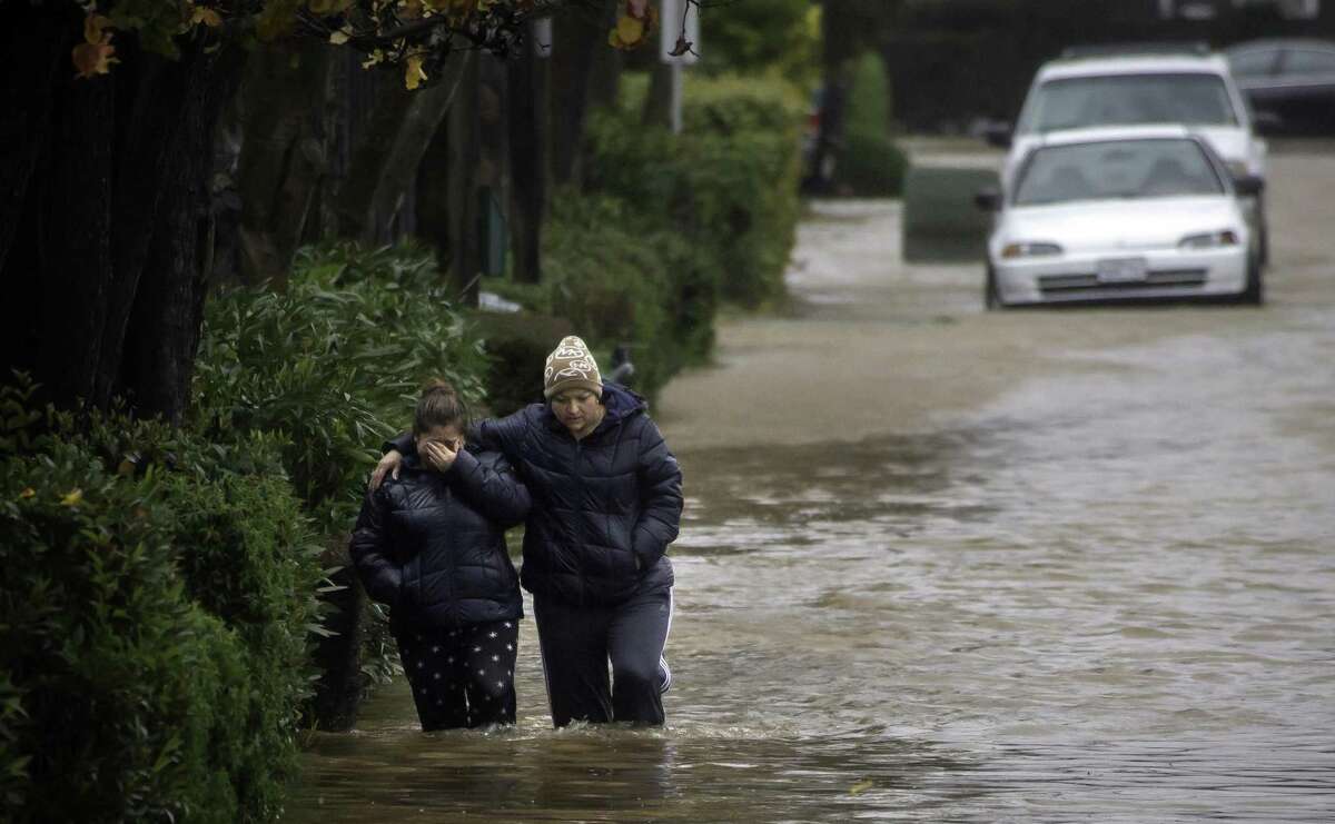 Two women brave waist-high floodwaters along Armstrong Avenue in Novato in January 2017.