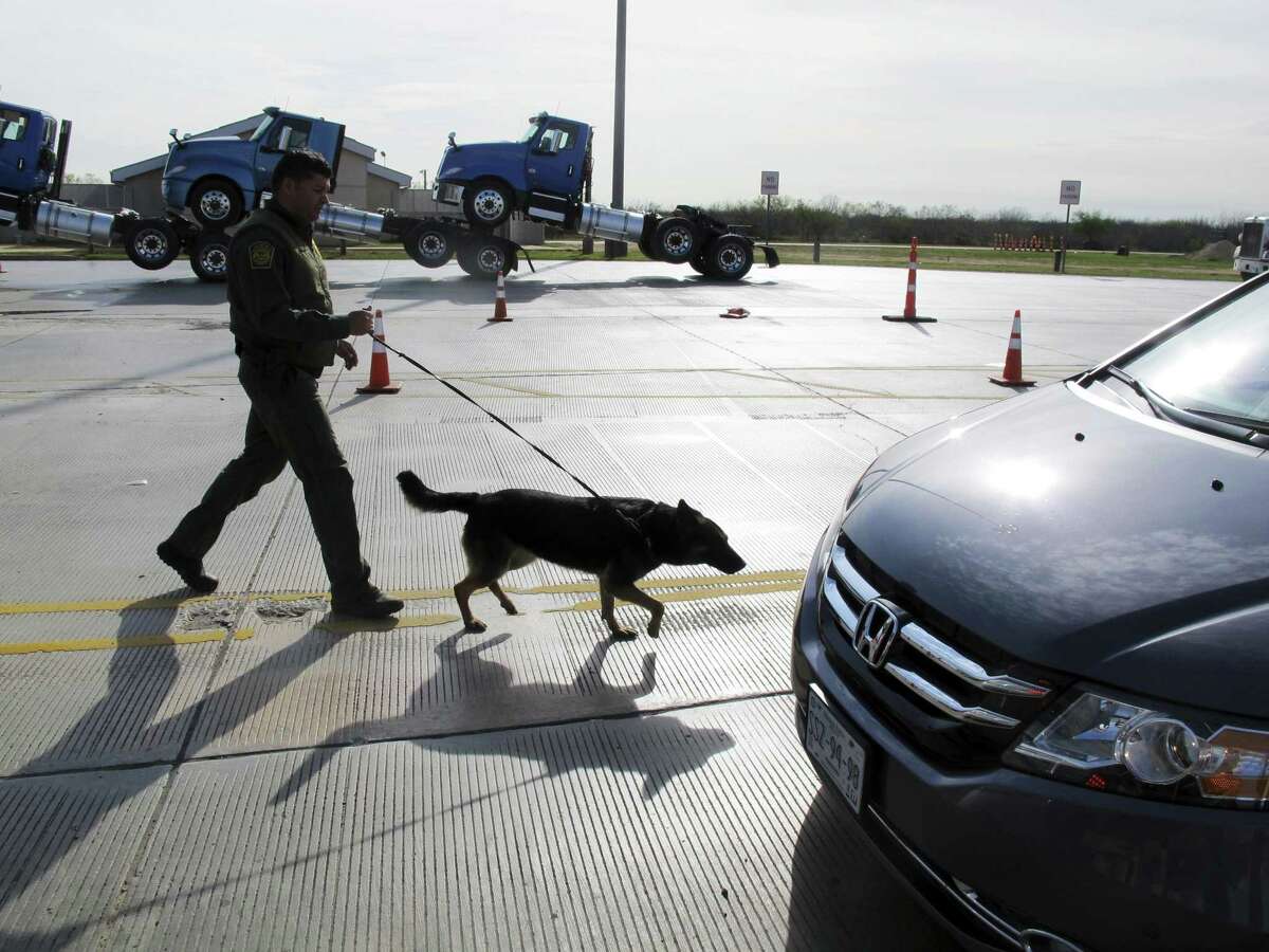 A Border Patrol agent uses a dog to inspect vehicles lining up at the Laredo North vehicle checkpoint in Laredo, Texas, on Friday, Feb. 2, 2018. The Border Patrol estimates that about 9,000 vehicles pass through their checkpoint every day, many coming north from Mexico.
