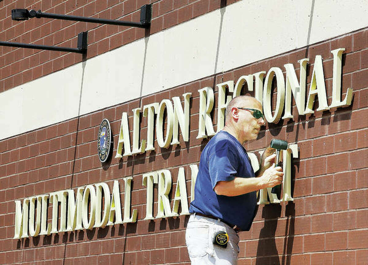 An employee of R.W. Boeker Co., Inc., in Hamel, uses a rubber mallot to tap a T into place for the lettering of the sign on the Alton Regional Multimodal Transportation Center last April.