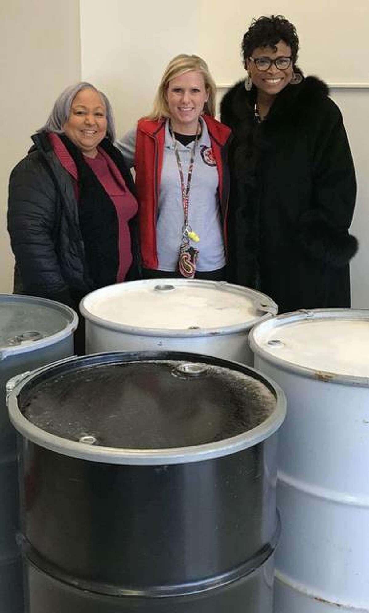Alderwoman Tammy Smith, 4th Ward; Principal Lanea DeConcini of East Elementary School; and the Rev. Sheila Goins with some of the metal drums the James Killion Beautification Enhancement Committee is having students decorate. The city will place the decorated bins at James H. Killion Park at Salu this spring. Smith and Goins are members of the committee.