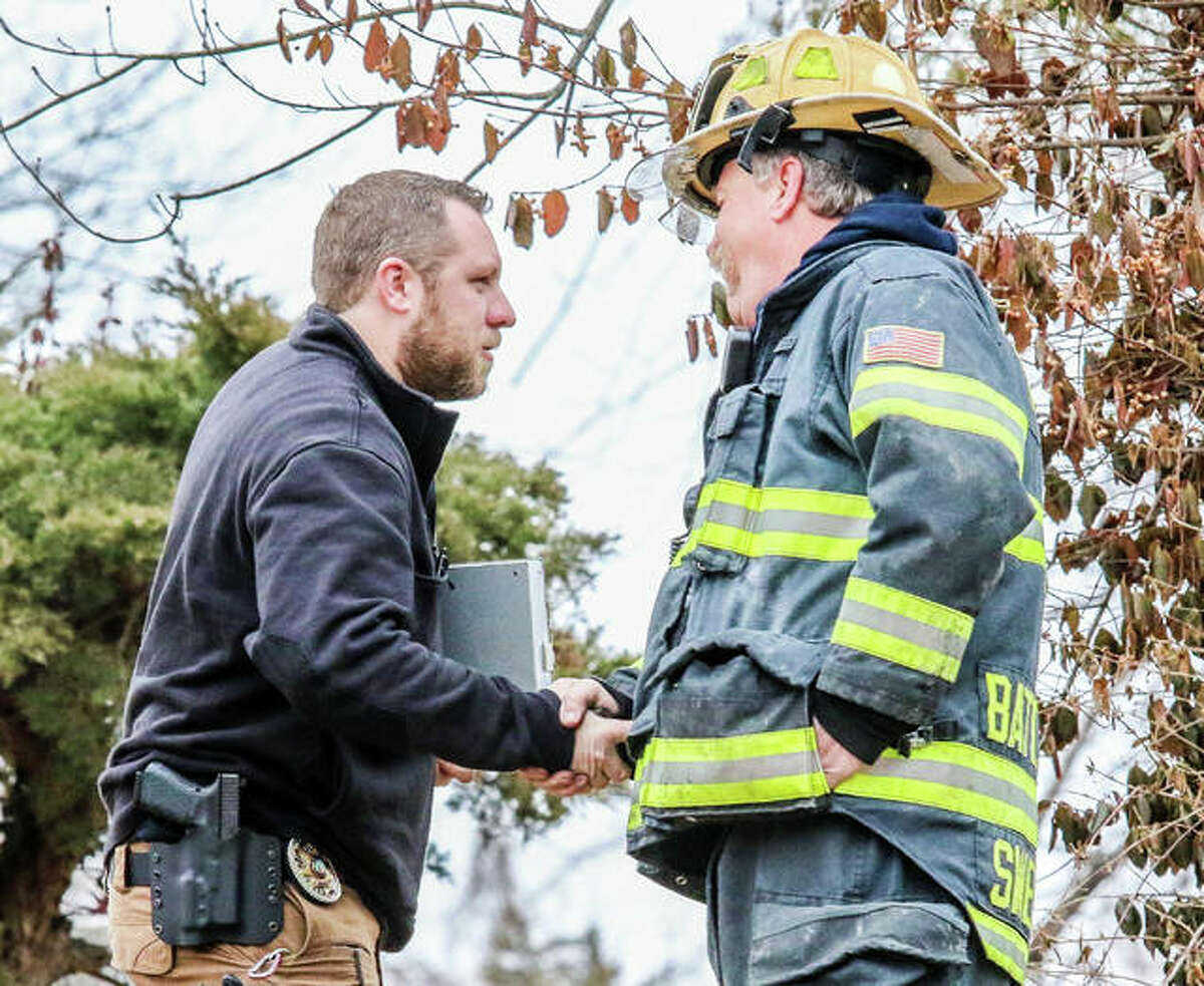 Alton Fire Department Battalion Chief Brad Sweetman, right, speaks to an investigator from the Illinois State Fire Marshal’s office Saturday afternoon as he arrives on the scene of a small fire where an Alton man was found deceased at 2309 Amelia St.