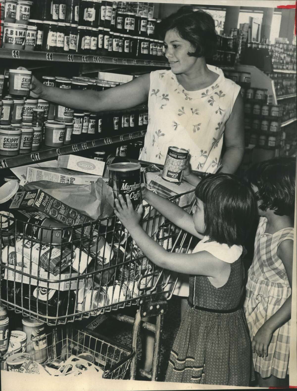 Sept. 9, 1965Grocery lists had extra items hastily added to them Thursday as housewives stocked up on canned goods and other nonperishable foods in case Hurricane Betsy hits this area. Mrs. A. R. Sanchez, 2603 W. Dallas, got help from daughters Sandy, rear, and Debbie as she shopped at a downtown supermarket. Included in her purchases were more canned goods, large cans of coffee, and spreads for sandwiches, including lots of peanut butter.