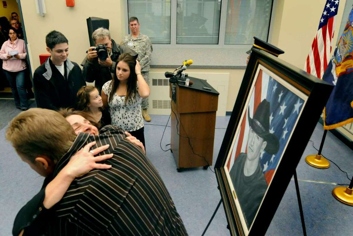 Vicki DiMura, mother of the late Sgt. David M. Fisher, who was killed while on patrol in Iraq on Dec. 1, 2004, when the vehicle he was riding in overturned, gets a hug from artist Phil Taylor of The American Fallen Soldier Project. DiMura is presented with a portrait of her son during a ceremony at the New York State Division of Military & Naval Affairs in Latham. (Michael P. Farrell/Albany Times Union)