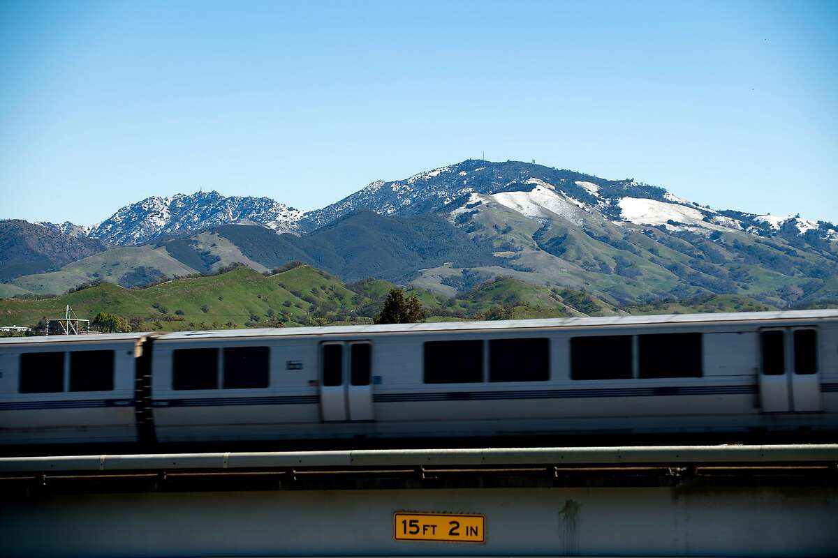 Snow caps the peaks of Mt. Diablo as a BART train passes through Walnut Creek, Calif., on Tuesday, Feb. 27, 2018.