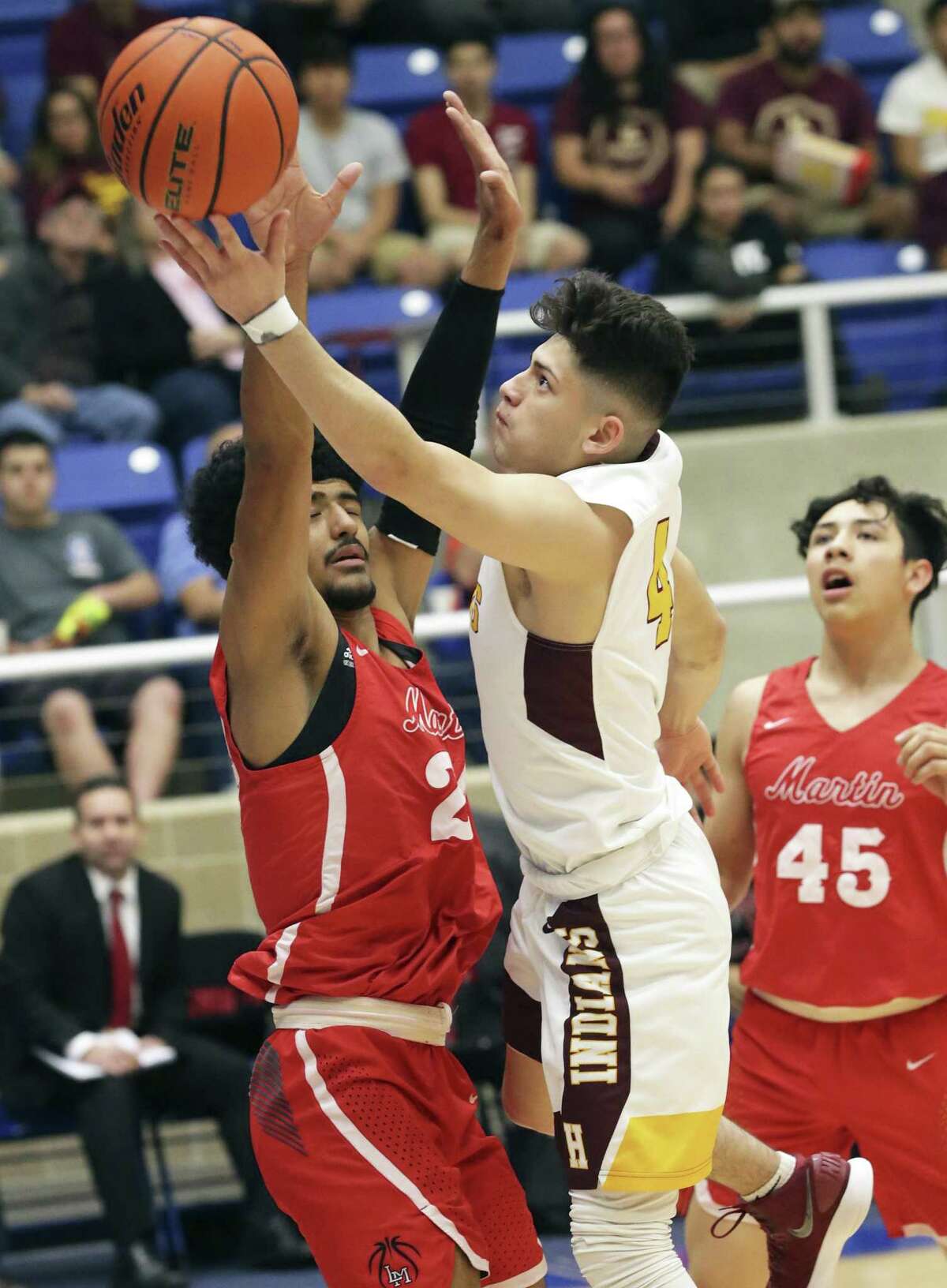 Indian guard Caleb Garcia stretches a shot at the hoop past Mathew Duron as Harlandale plays Laredo Martin in Class 5A third-round basketball playoffs at Northdise ISD Gym on February 27, 2018.