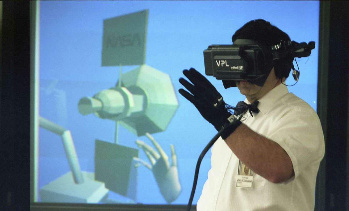 04/24/1992 - At Johnson Space Center, NASA scientist Bowen Loftin, working with virtual reality, gestures with a DataGlove, causing the hand on the screen - and on TV images in his headset - to respond in kind.