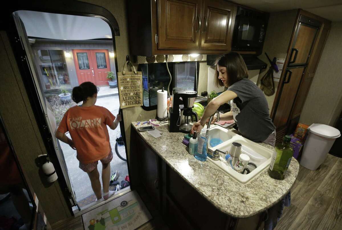 Jennifer Coulter prepares dinner as her daughter, Luke Coulter, 9, left, Chloe Coulter, 11, steps out of the travel trailer parked outside their flooded Kingwood home Wednesday, Feb. 28, 2018. They are living in the travel trailer in the driveway of their home while waiting for their house to be rebuilt after flooding from Hurricane Harvey.